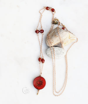 Gold and red necklace with a white background