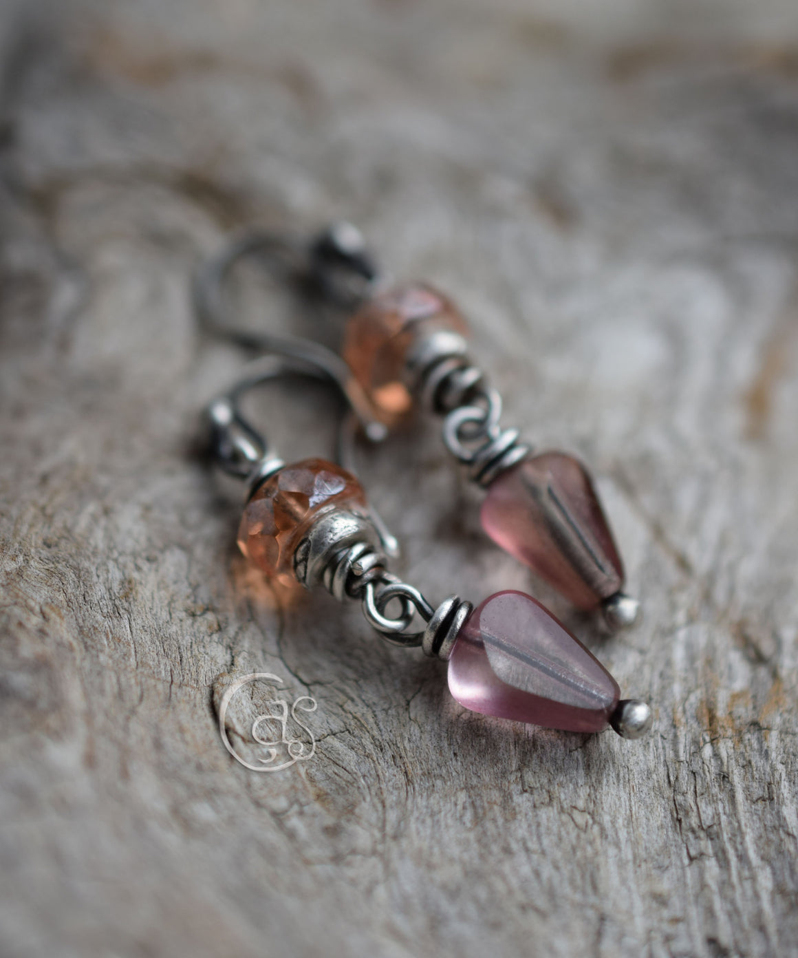 Peach and rose beaded silver earrings on a wood background. 