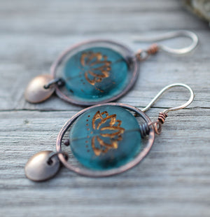 Copper hoop earrings with blue glass lotus beads at the center with golden highlights. Brass circle dangles. Bohemian Style Earrings that are handmade.